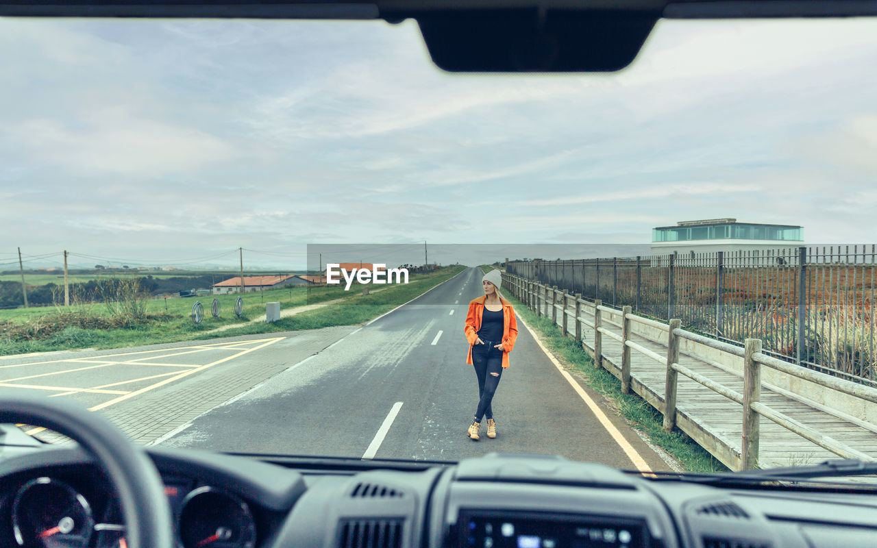 View from inside camper van of woman posing on the road