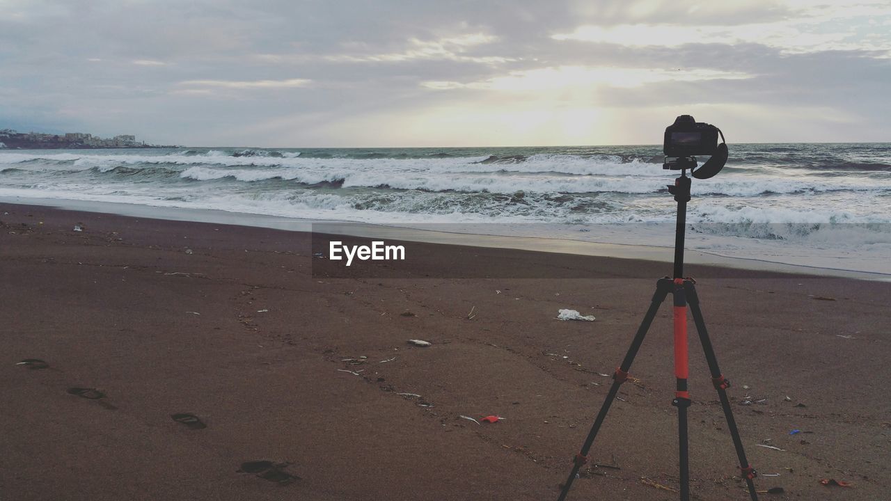 Camera and tripod on beach during sunset