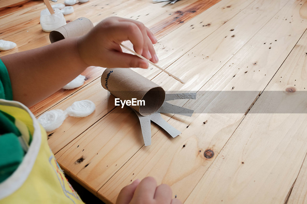 HIGH ANGLE VIEW OF PERSON HOLDING PAPER WITH TEXT ON TABLE