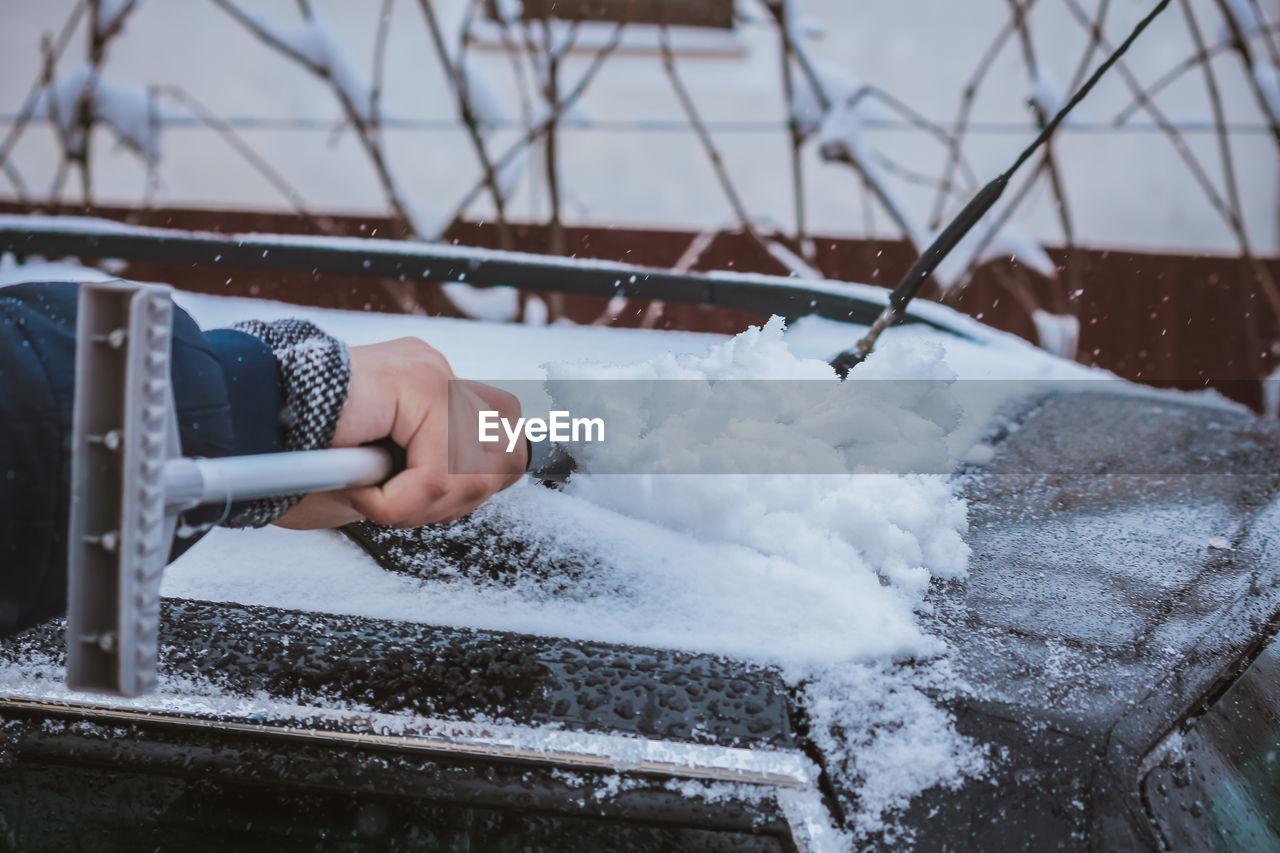 Young teen cleaning snow from the back of the car