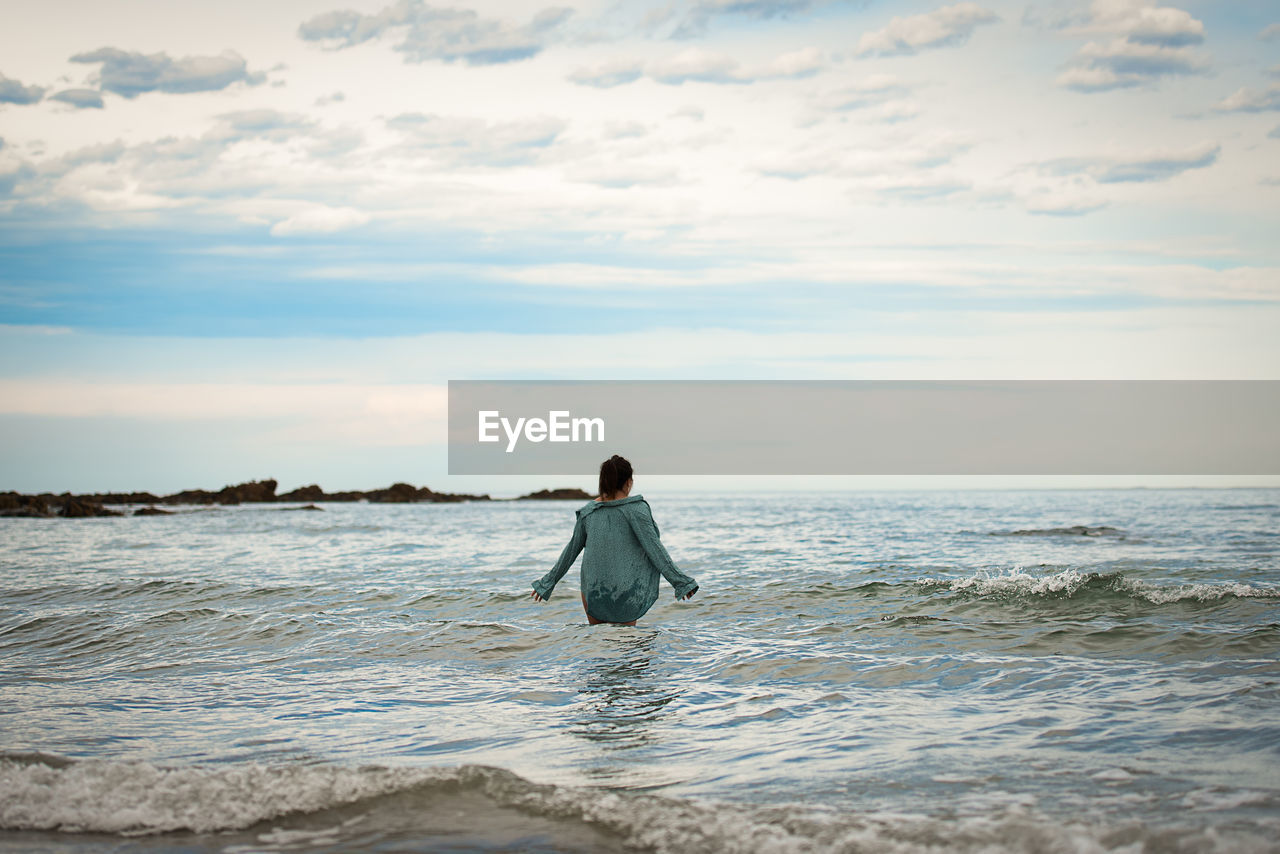 Rear view of man on beach against sky