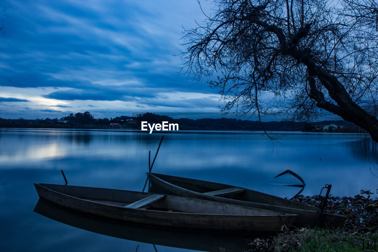 BOAT MOORED ON LAKE AGAINST SKY