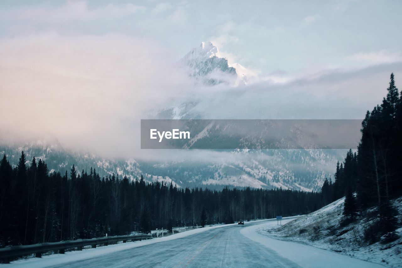 Road amidst snowcapped mountains against sky during winter