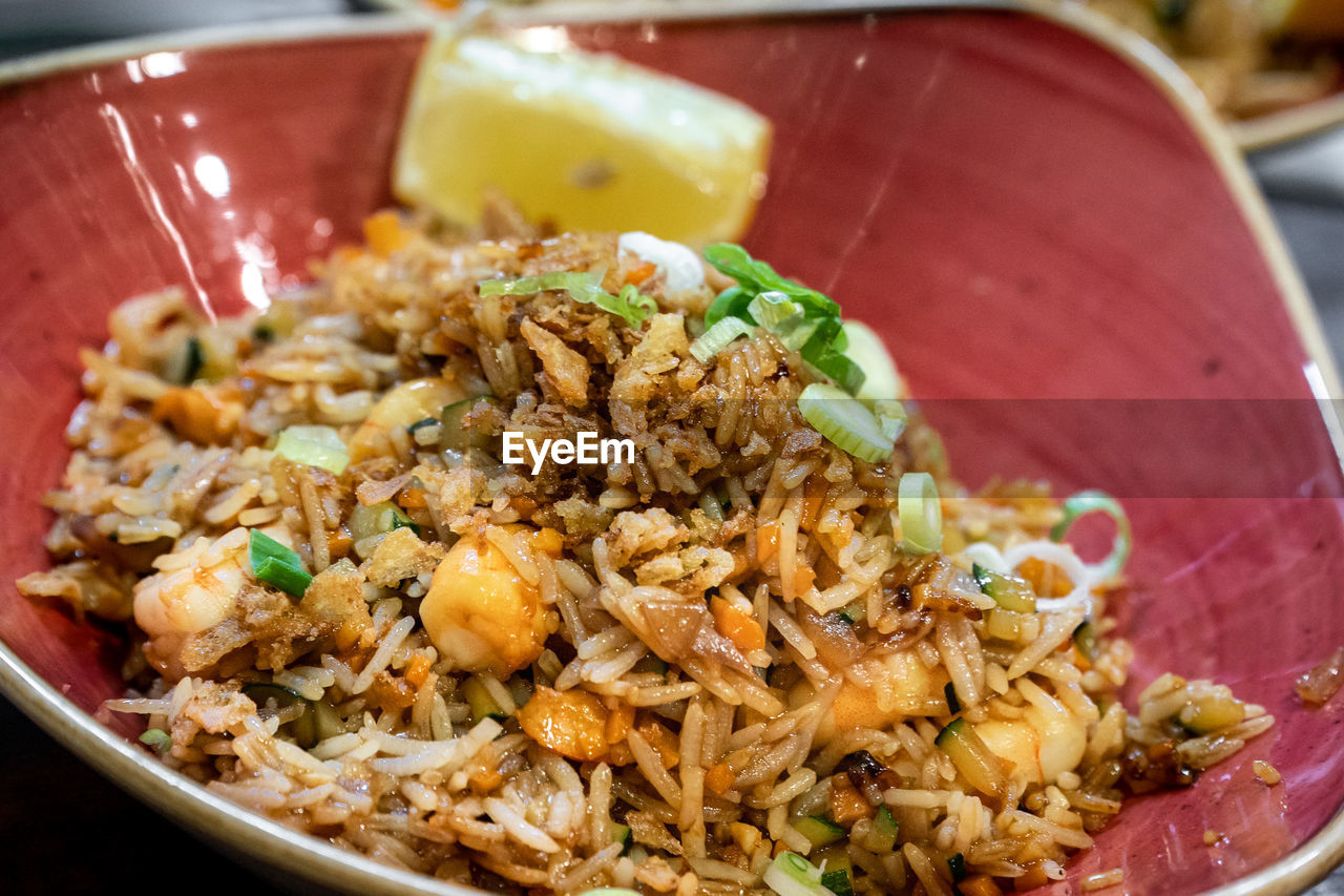 A tasty bowl of oriental style prawn fried rice served with a lemon wedge close up