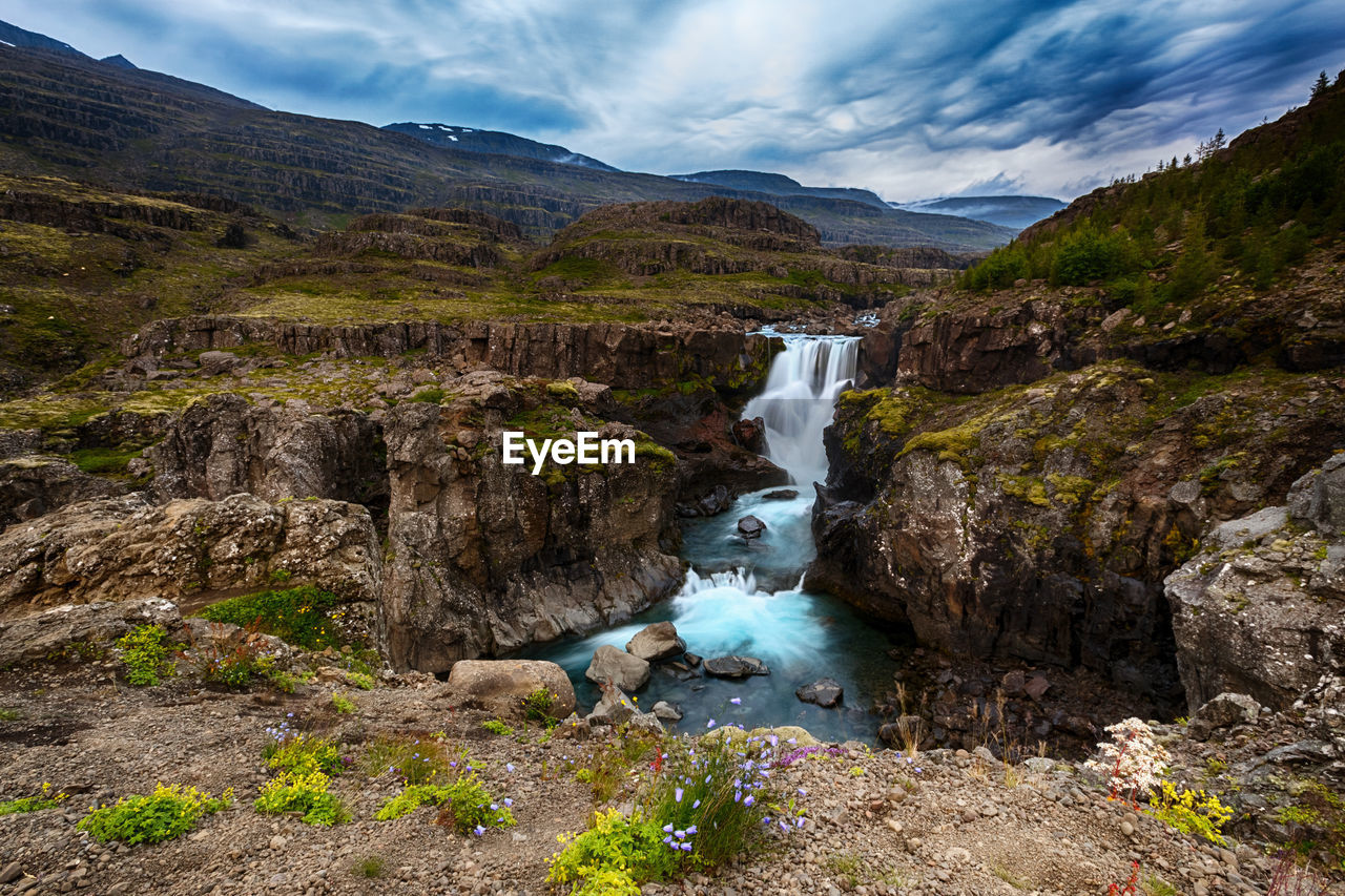 SCENIC VIEW OF WATERFALL AGAINST SKY