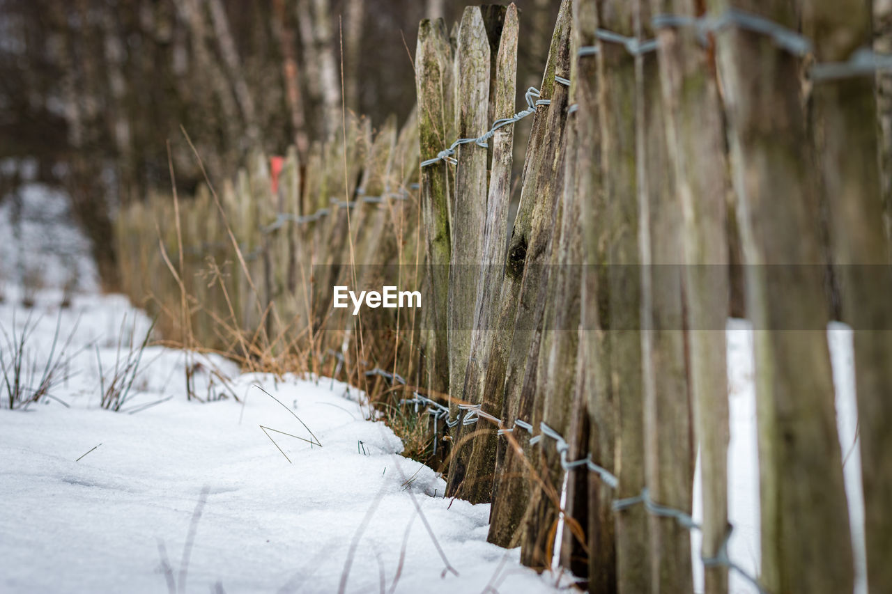 Wooden fence on snow covered field