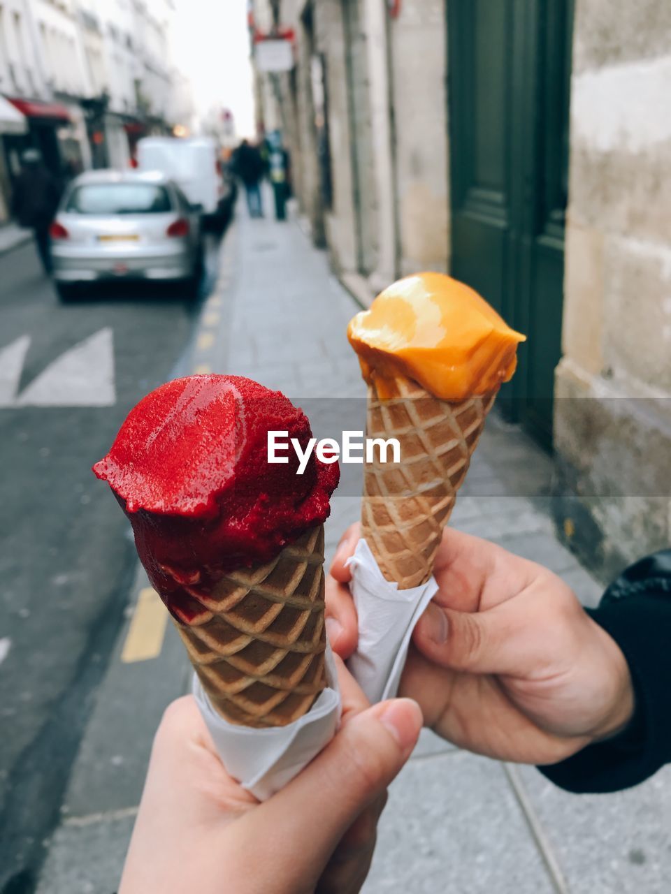 Cropped hands of people holding ice cream cones in city