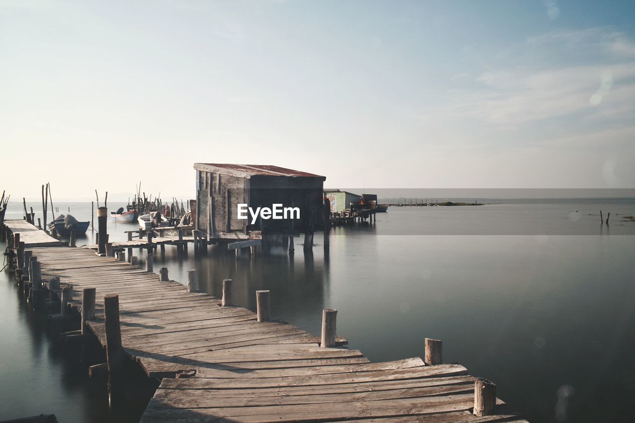 Wooden jetty on pier over sea against sky