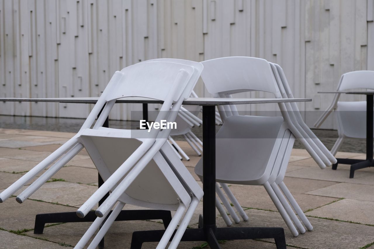 Empty chairs and table against white wall