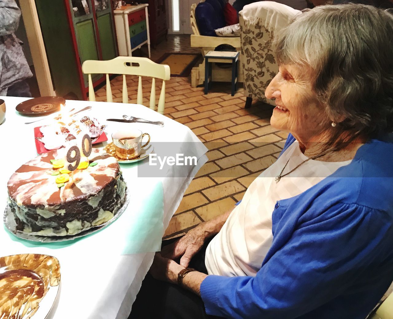 High angle view of senior woman sitting by birthday cake on table at home