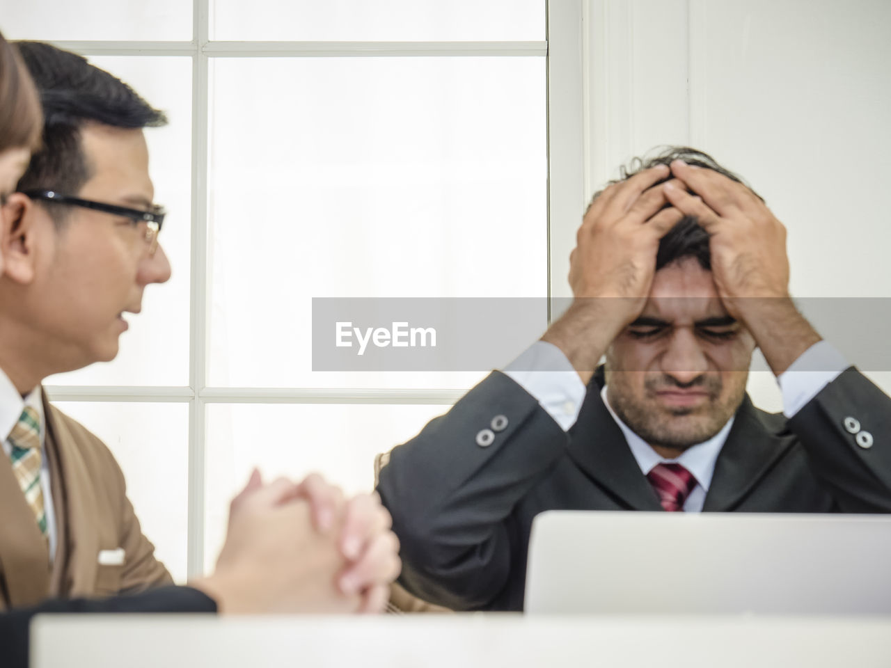 Colleague looking at frustrated businessman in office