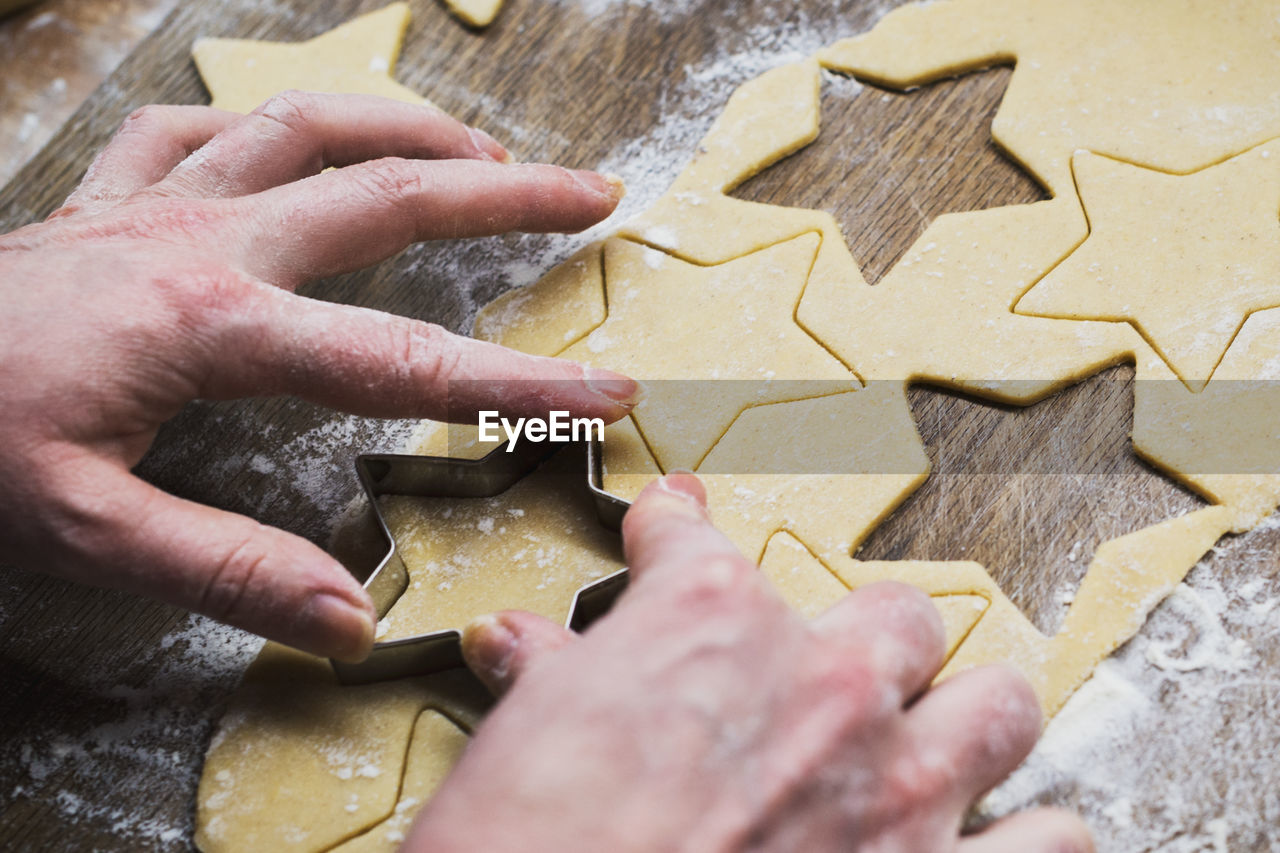 High angle view of woman hand cutting cookies on table