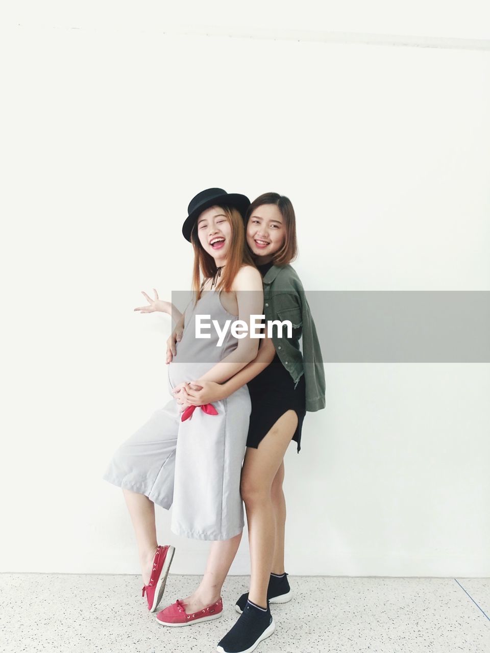 Portrait of smiling young women standing against wall