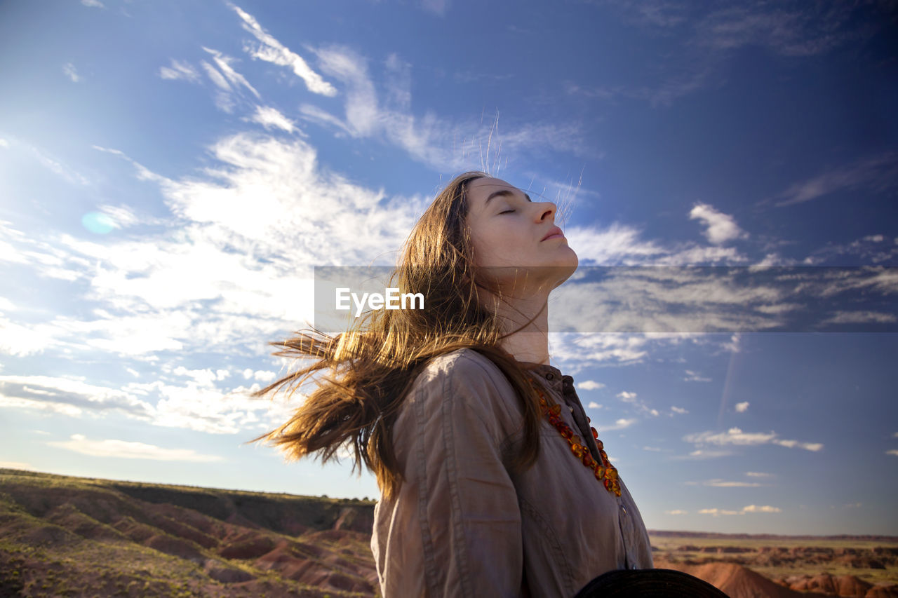 Female tourist with eyes closed standing against sky at petrified forest, national park, arizona, usa