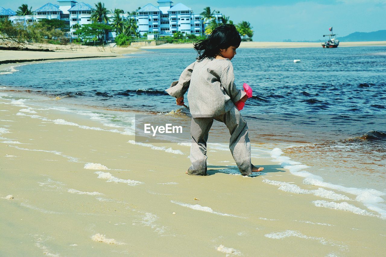 Full length of girl standing on shore at beach