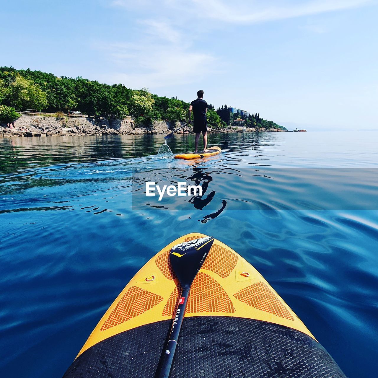 MAN STANDING IN BOAT AGAINST SKY