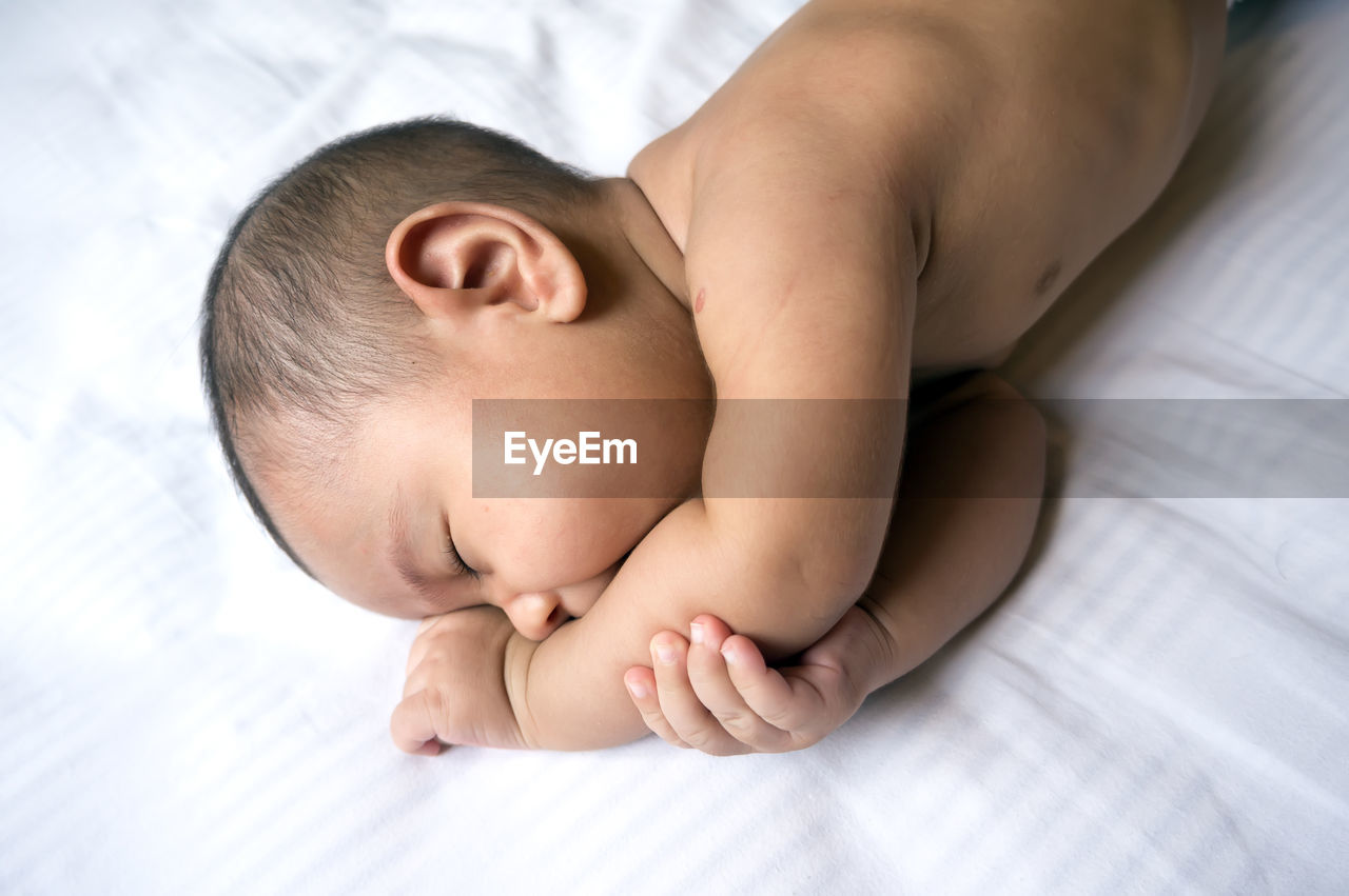 Close-up of baby lying on bed at home