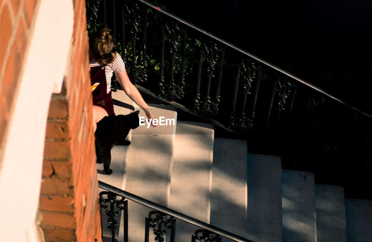 High angle view of woman with cat sitting on steps