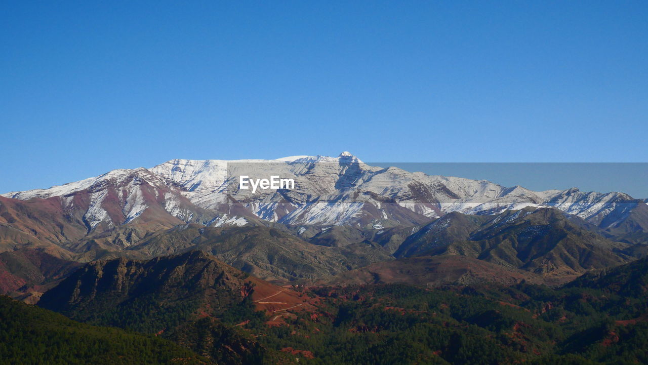 Scenic view of snowcapped mountains against clear blue sky