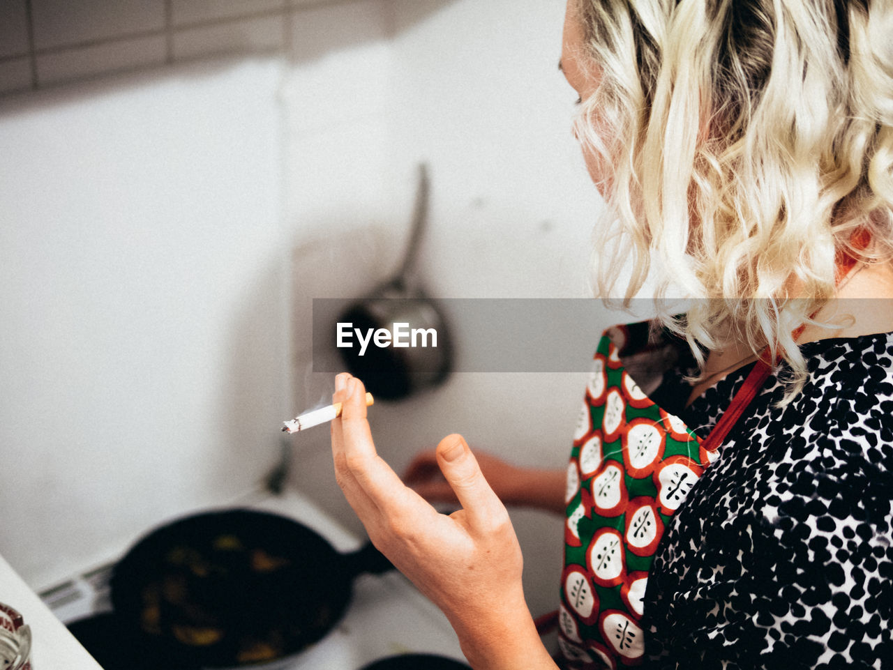 High angle view of woman smoking cigarette while cooking in kitchen