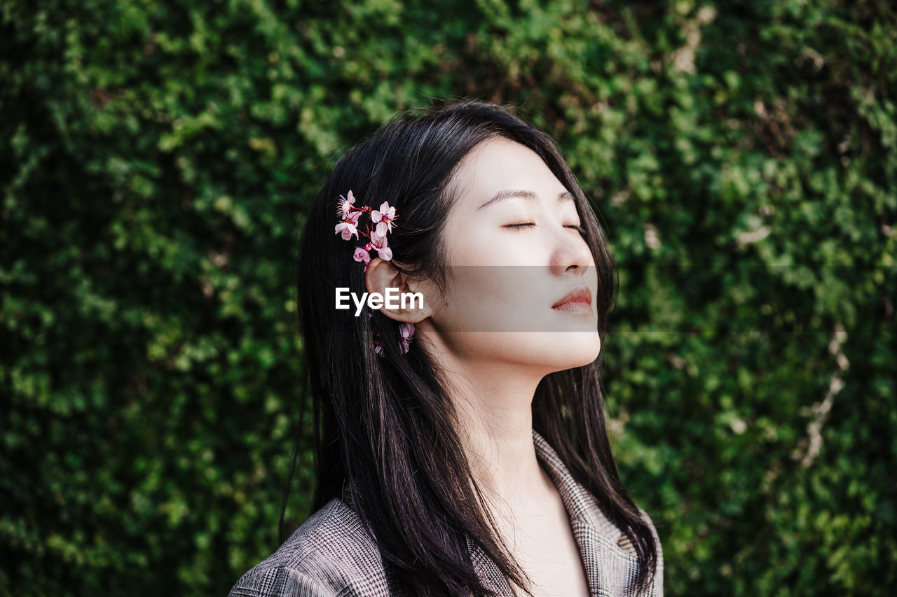 Portrait of beautiful chinese asian woman with eyes closed and almond tree flowers.spring time,relax