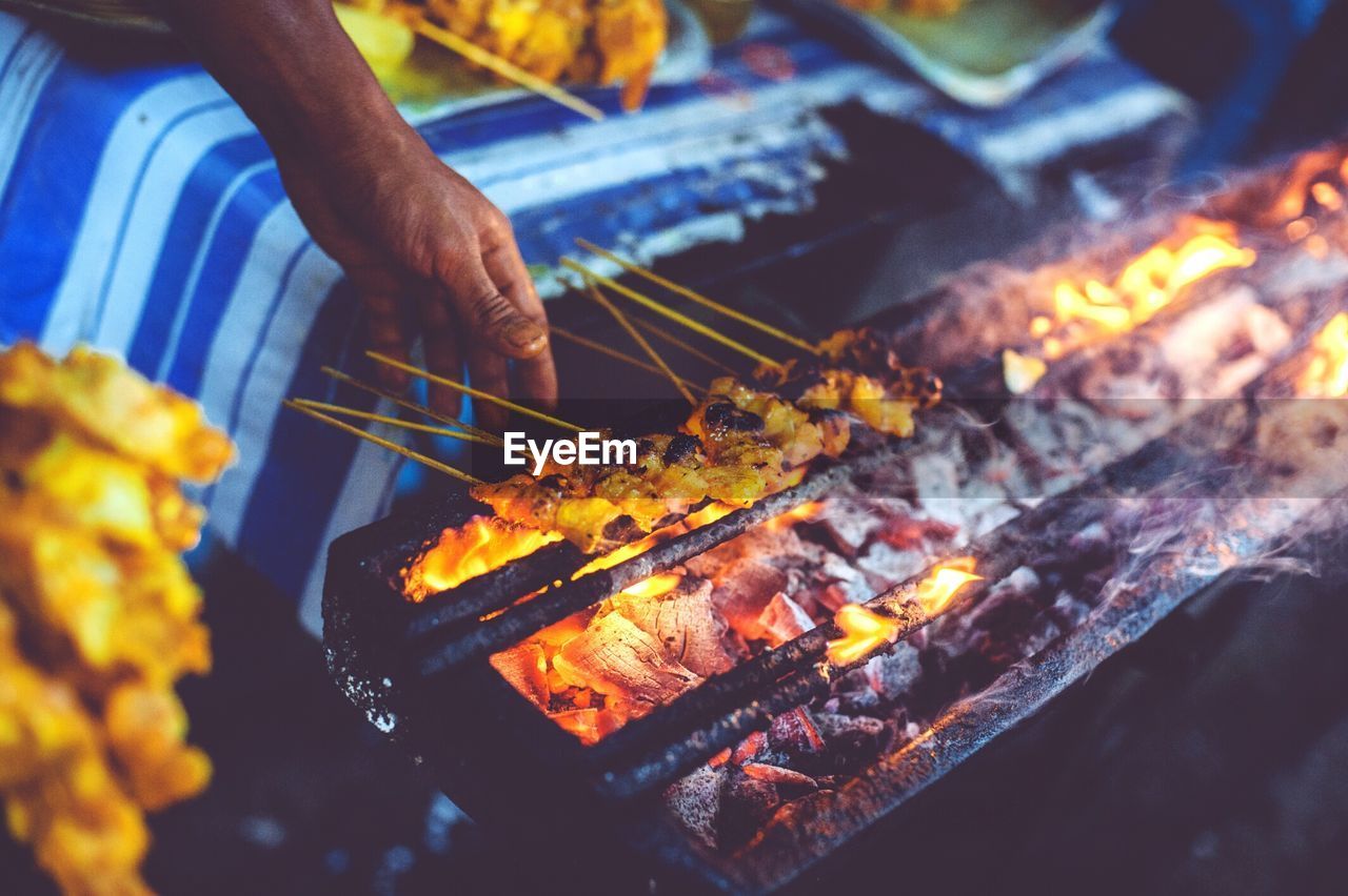 Cropped image of hand cooking satay on barbecue