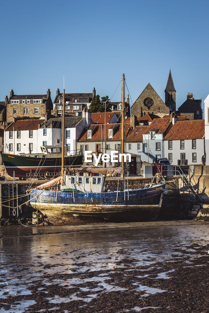 BOATS MOORED IN RIVER BY BUILDINGS AGAINST SKY