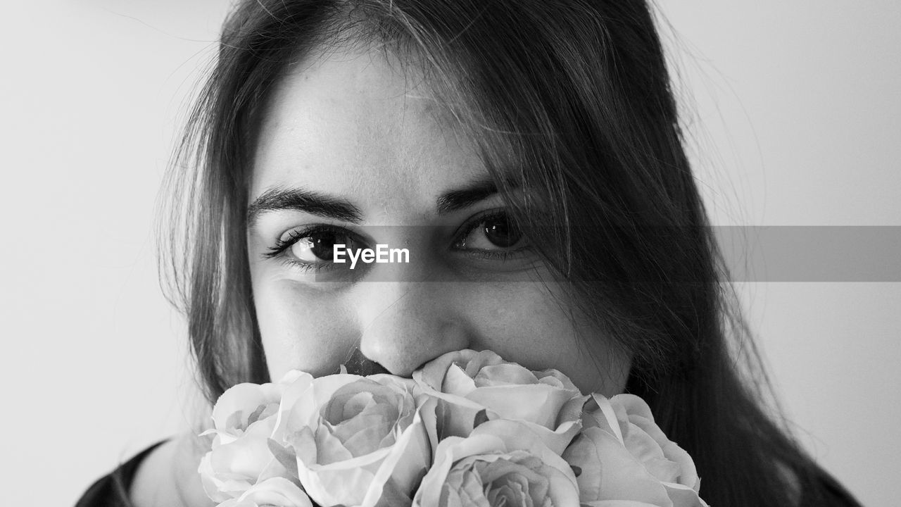 CLOSE-UP PORTRAIT OF A BEAUTIFUL YOUNG WOMAN HOLDING WHITE FLOWER