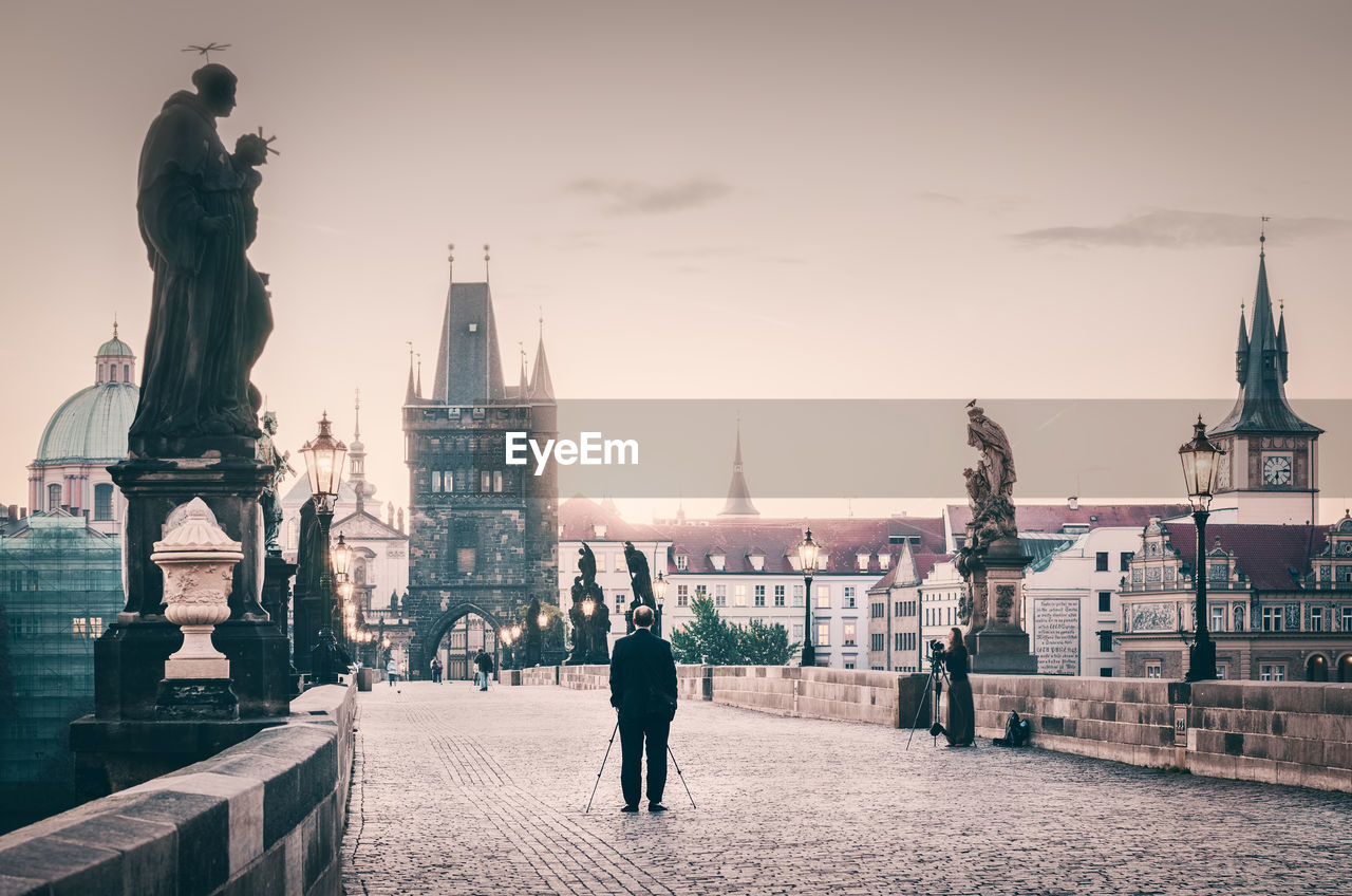 Rear view of man with walking cane on charles bridge against sky