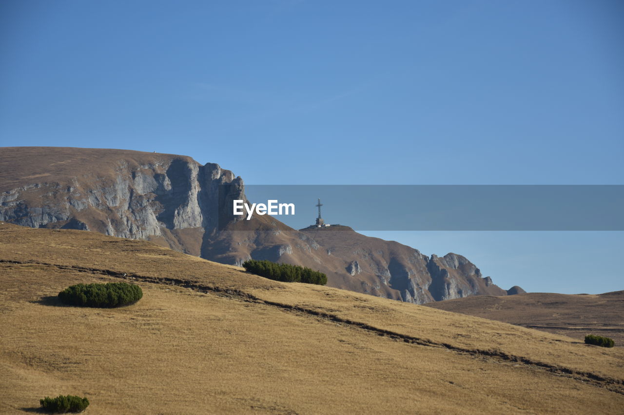 Scenic view of arid landscape against clear blue sky