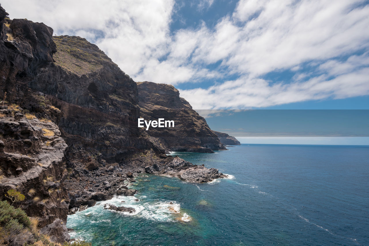 Rock formations by sea against sky