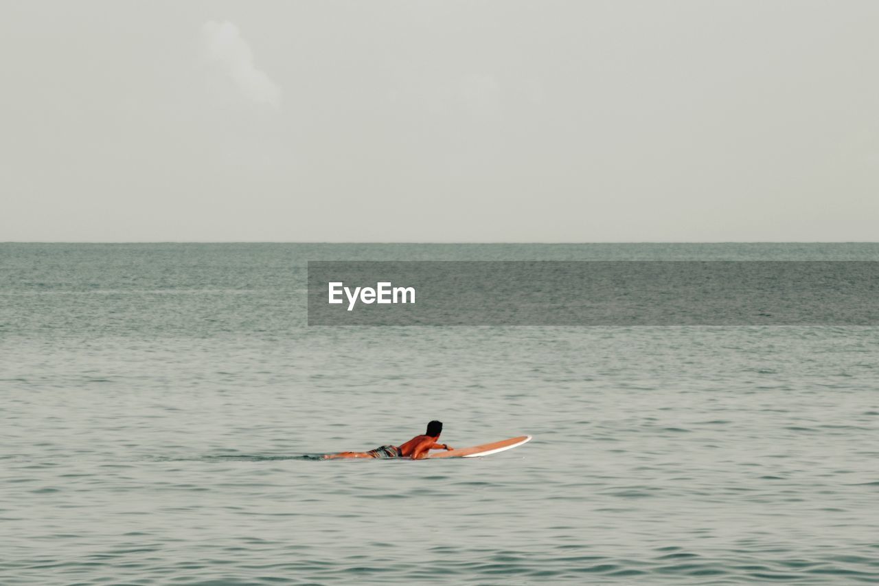 Man on surfboard in sea against sky