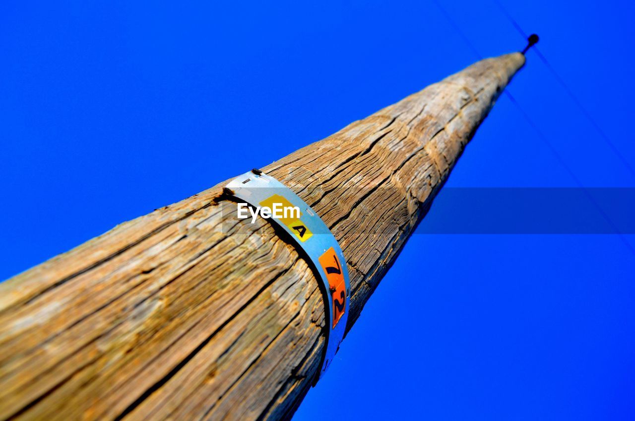 Low angle view of old bamboo against clear blue sky