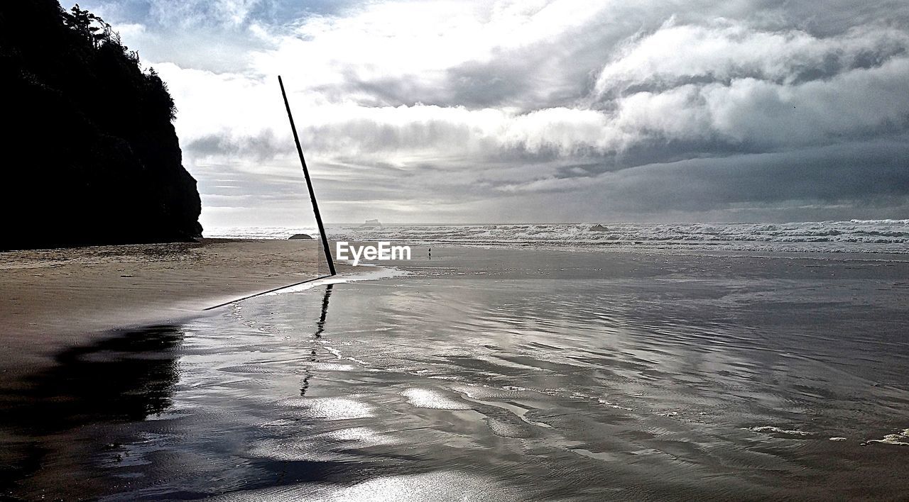 Beach by sea against cloudy sky