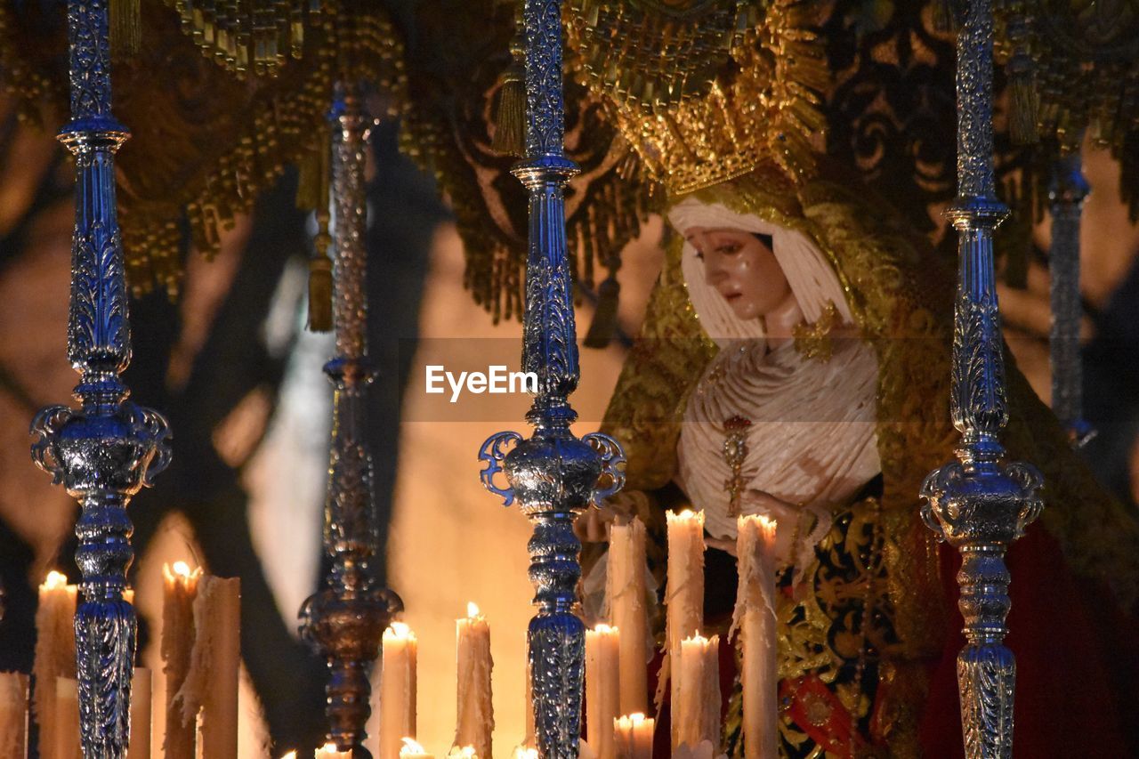 Lit candles by virgin mary sculpture in church