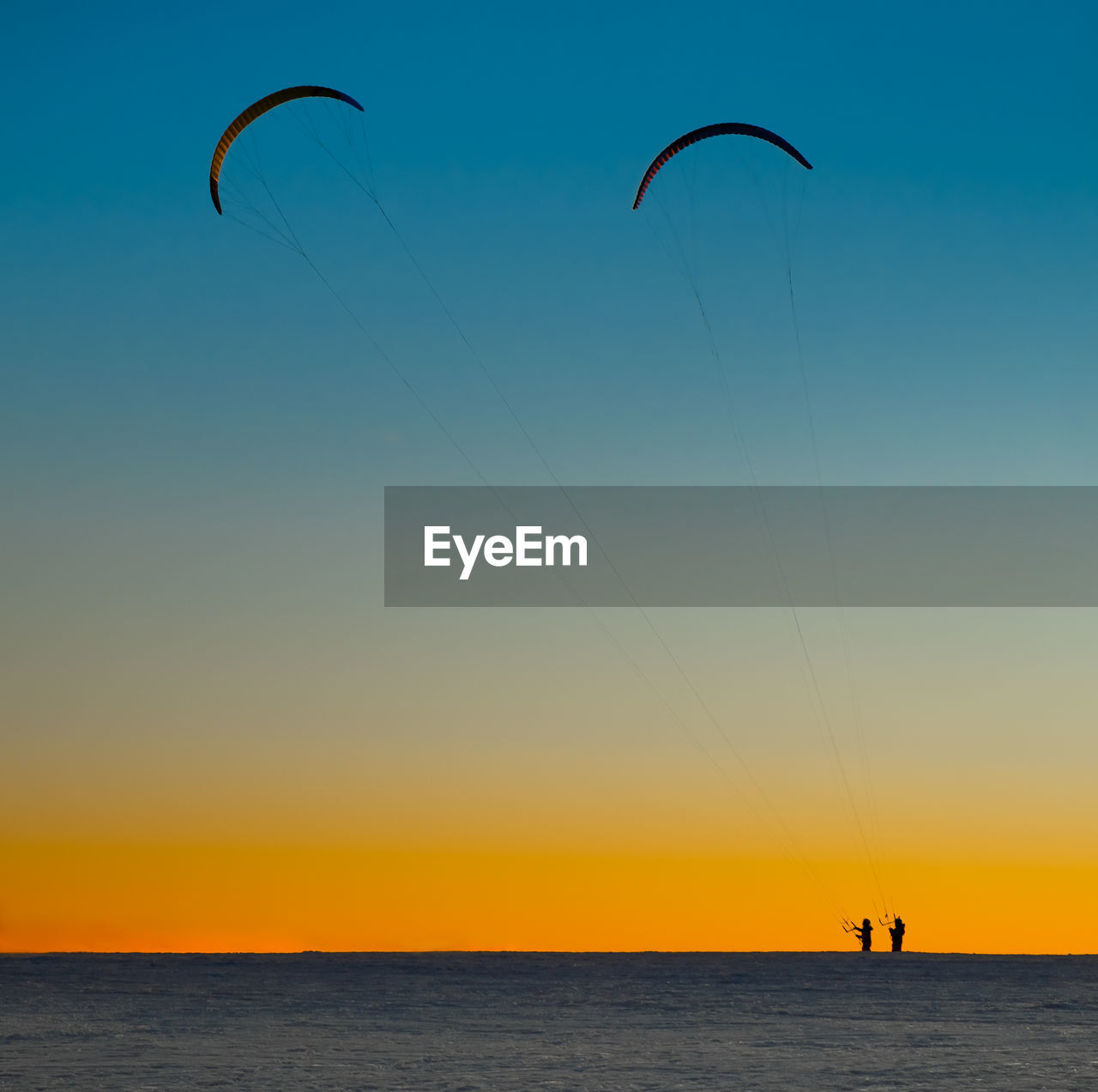 Scenic view of snow against sky during sunset with paragliders