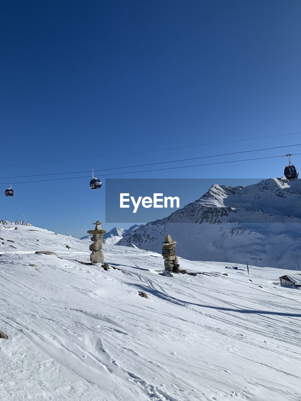 Overhead cable car against snowcapped mountains against clear blue sky