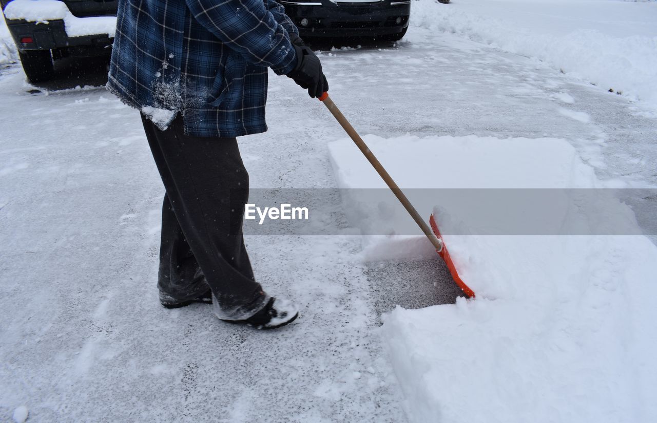 LOW SECTION OF MAN ON SNOW COVERED LANDSCAPE DURING WINTER