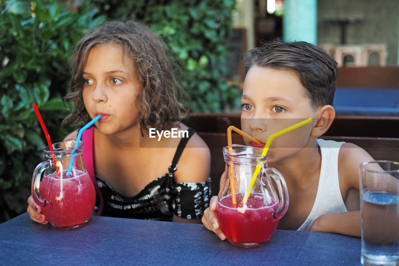 Siblings drinking juice at restaurant