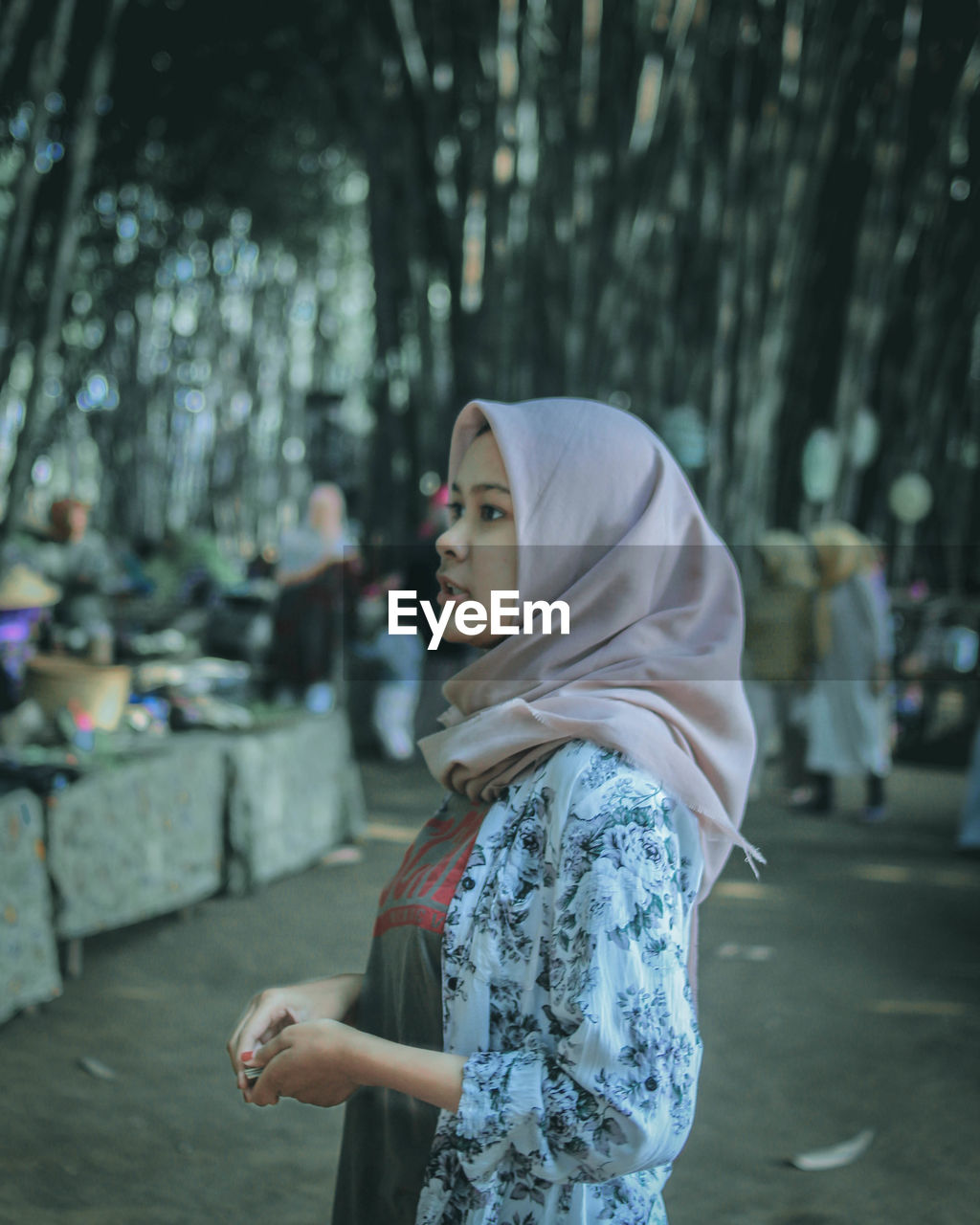 Teenage girl wearing hijab looking away while standing in city