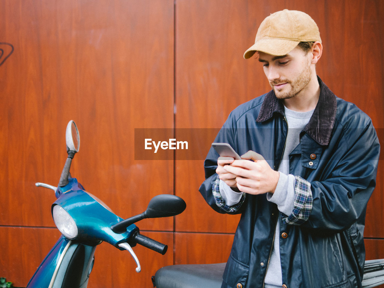 Young man standing by scooter in city