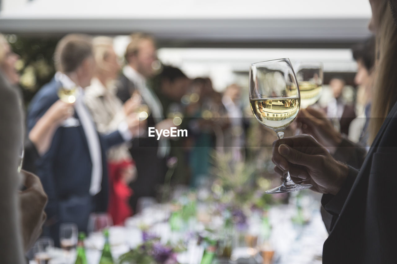 Close-up of man holding wineglass at part