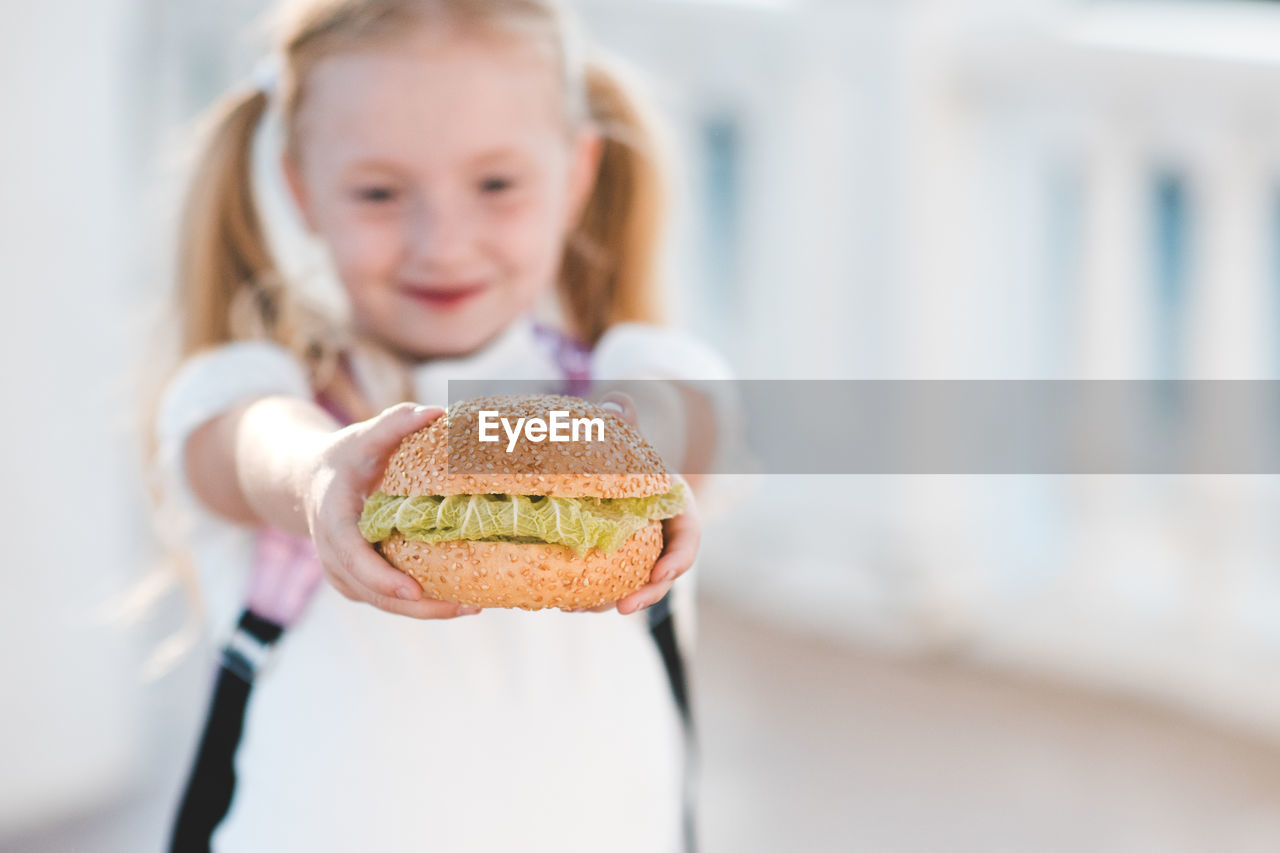 Girl hold fresh hamburger with lettuce closeup. fast food. junk food. back to school. good morning