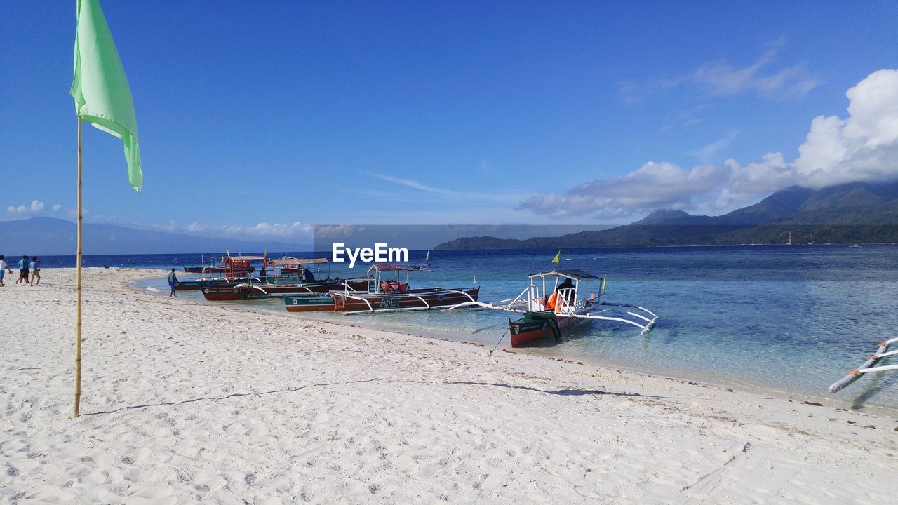 Outrigger boats at beach against sky