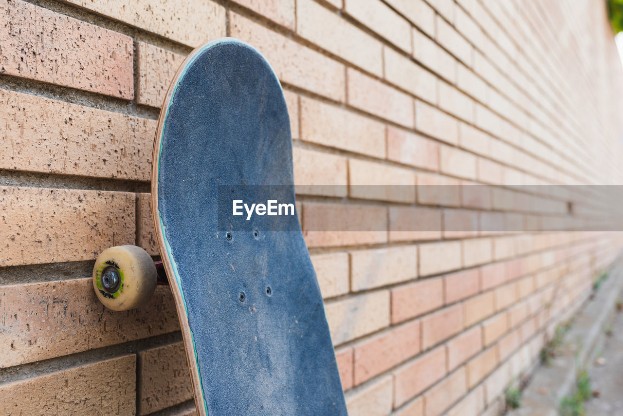 Skateboard supported on a brick wall.