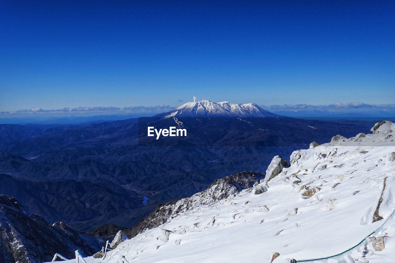 Scenic view of snowcapped mountains against clear blue sky