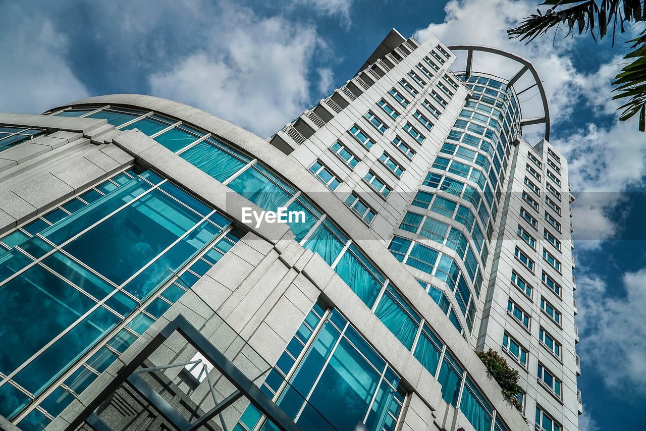 LOW ANGLE VIEW OF MODERN GLASS BUILDING AGAINST SKY