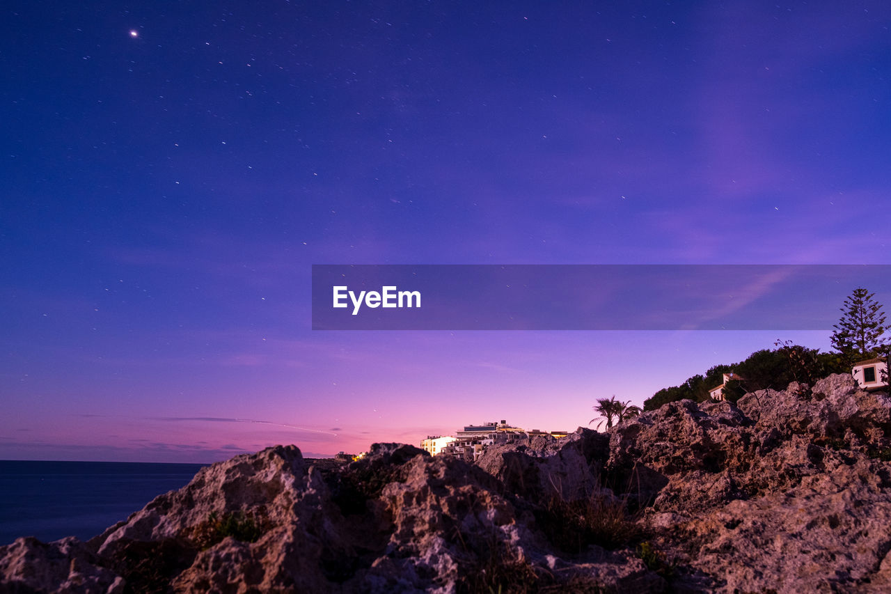 View at dawn of purple sky with stars and rocky pier in mallorca. 
