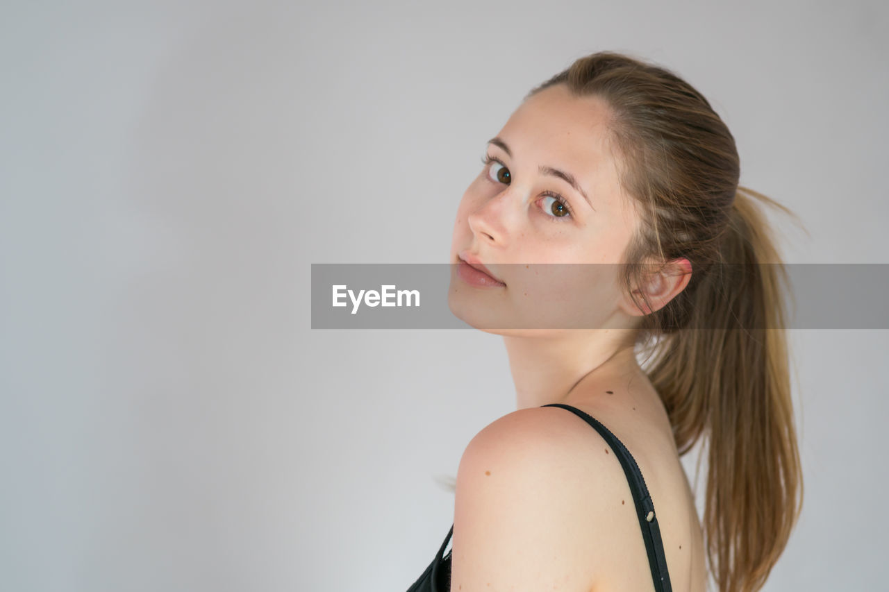 PORTRAIT OF BEAUTIFUL WOMAN AGAINST WHITE BACKGROUND