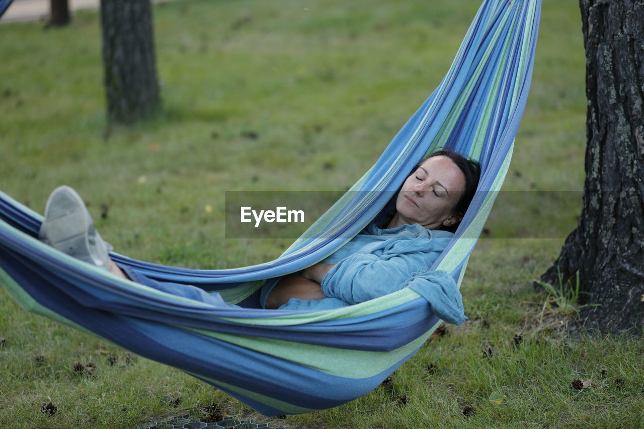 Woman sleeping on hammock in field